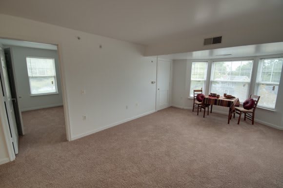 An unfurnished room with a small dining setup near the windows.