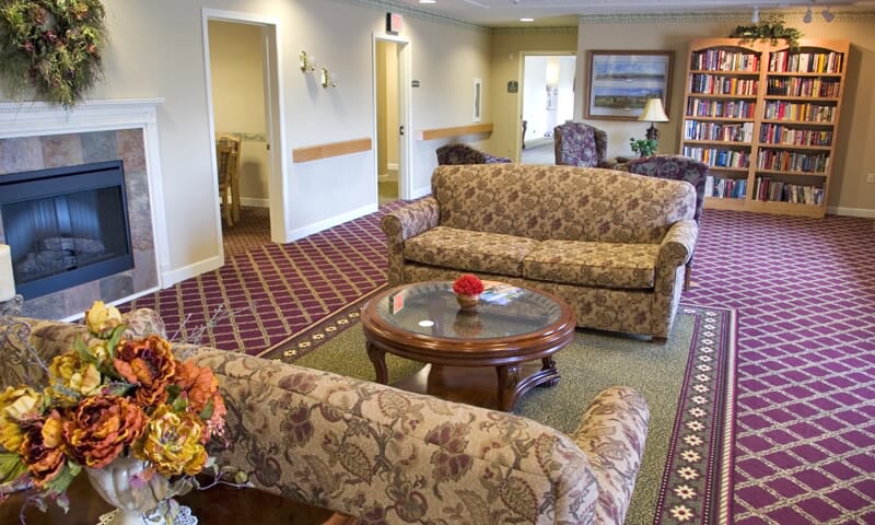 A cozy lounge area with patterned sofas and a wooden coffee table on a red carpet.