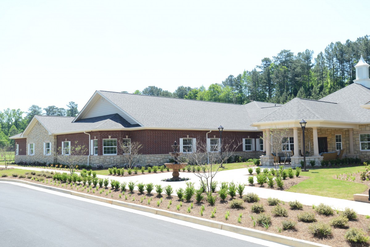 A modern brick building with a well-maintained landscape and adjacent road.
