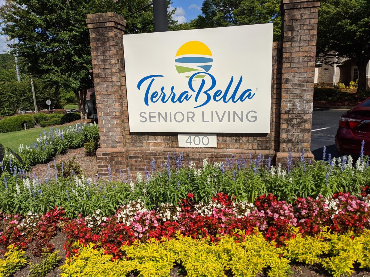 Entrance sign of Terra Bella Senior Living surrounded by vibrant flowers.