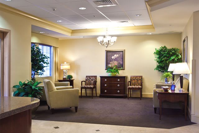 A spacious and well-decorated waiting room with comfortable seating and lush greenery.