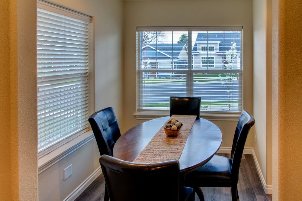 A cozy dining area with a wooden table and four chairs by the window, allowing natural light to fill the room.