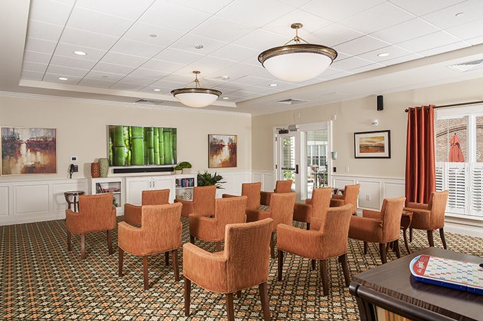 A well-arranged conference room with orange chairs, a large TV, and decorative artwork.