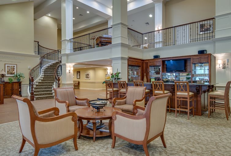 A luxurious hotel lobby featuring elegant seating, a staircase, and a bar area.