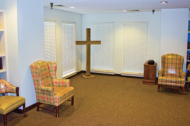 A simple chapel interior featuring a cross and a single chair.