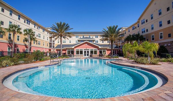 A luxurious resort with a pristine swimming pool surrounded by palm trees.