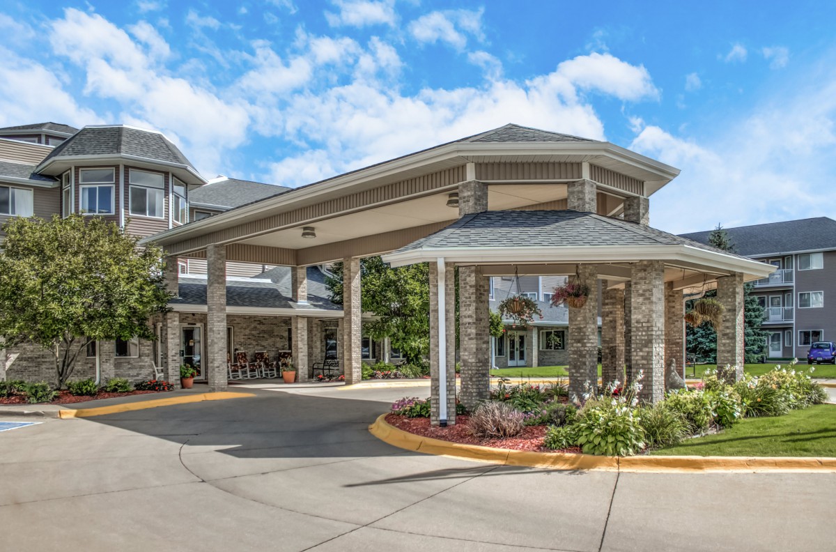 A welcoming building entrance with a covered driveway and well-maintained landscaping.