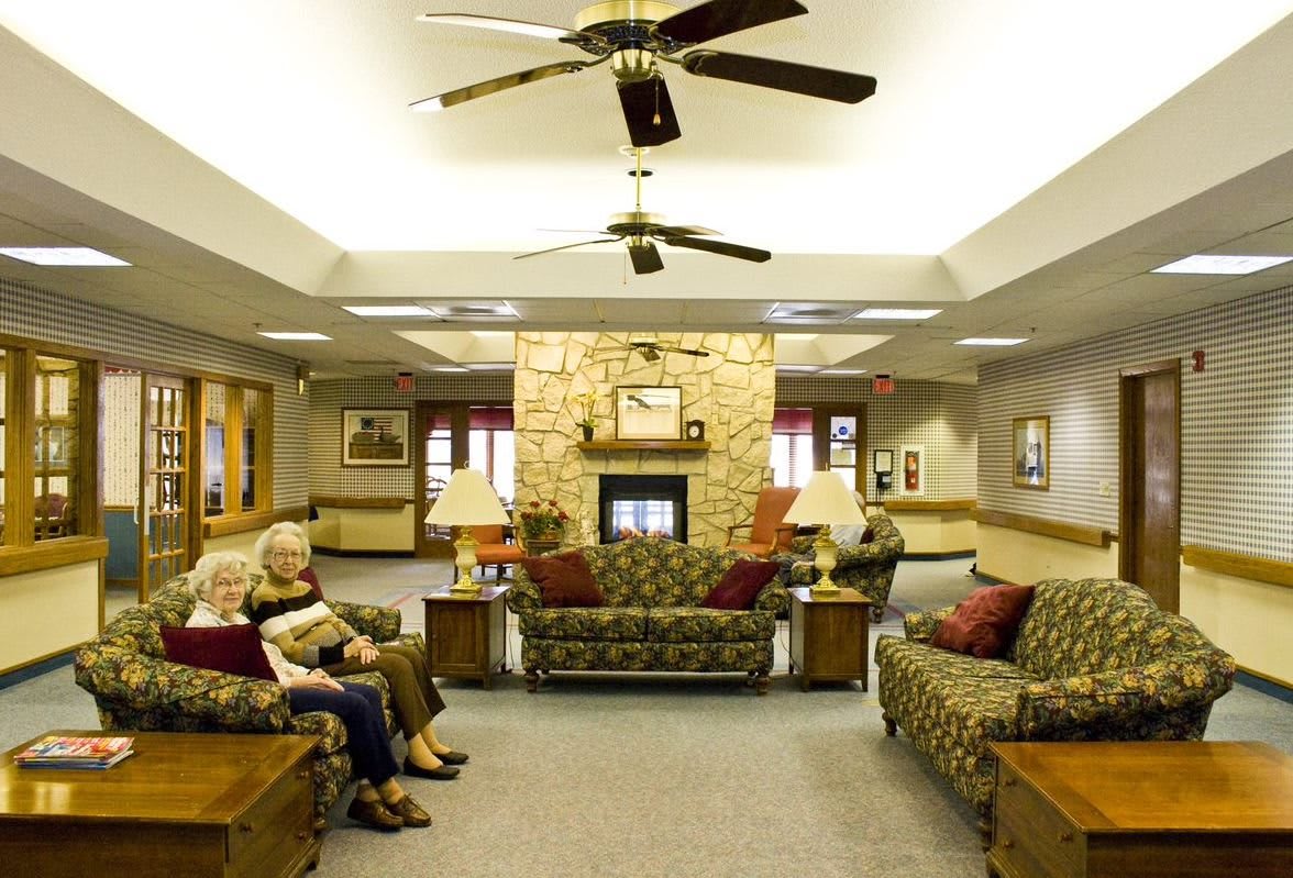 A spacious lounge area featuring sofas, a fireplace, and ceiling fans.
