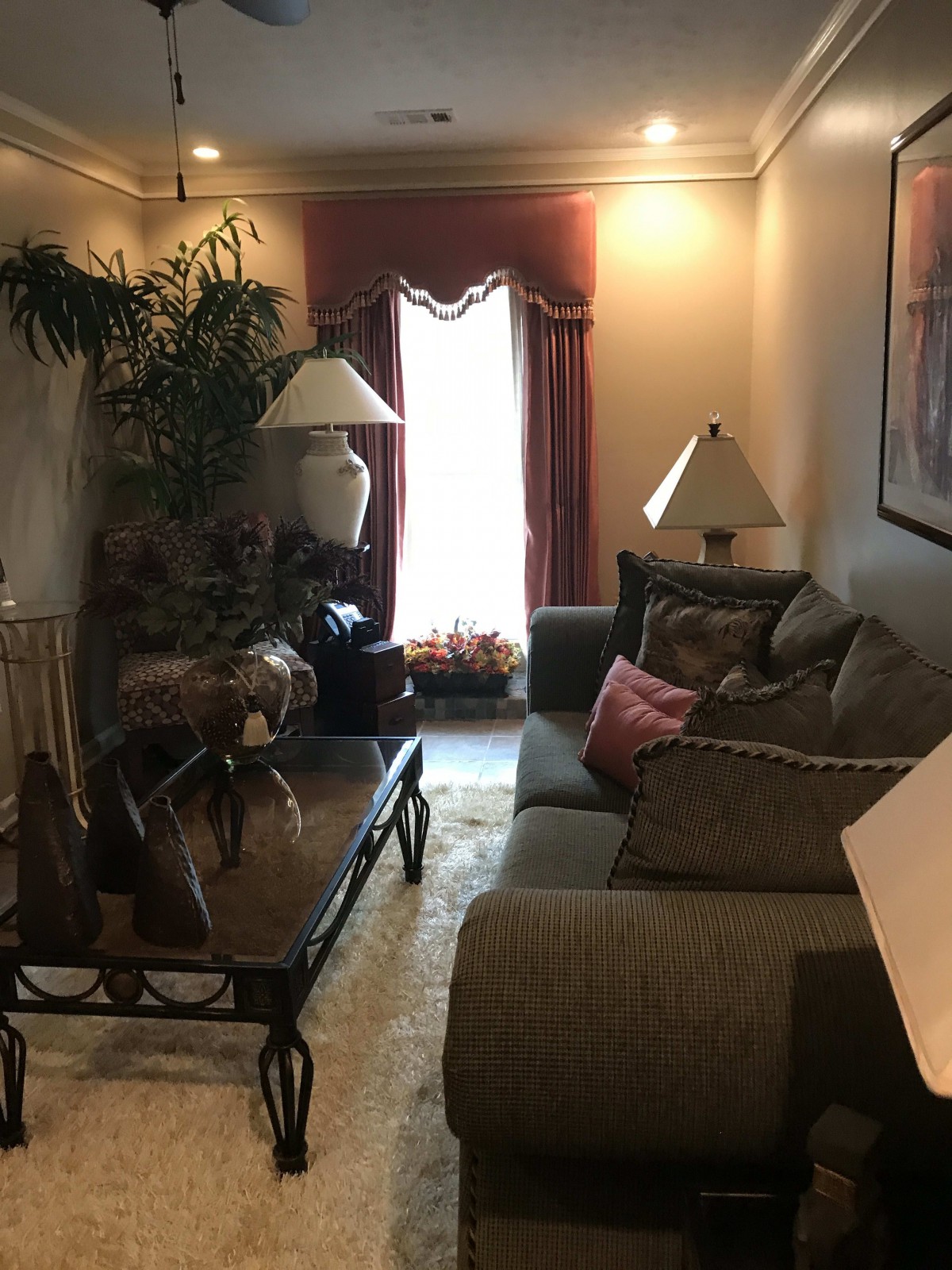A cozy living room with a sofa, lamps, and a coffee table, featuring warm lighting and decorative elements.