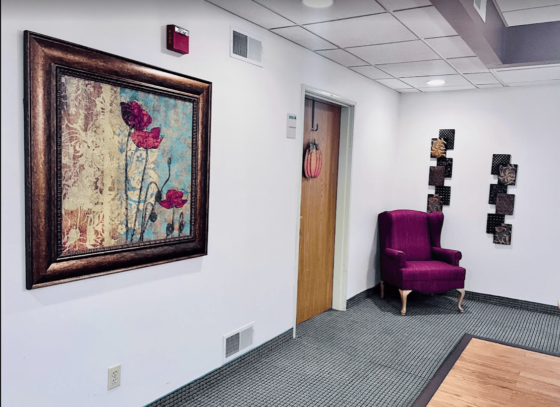 A nicely decorated office hallway featuring artwork and a purple chair.