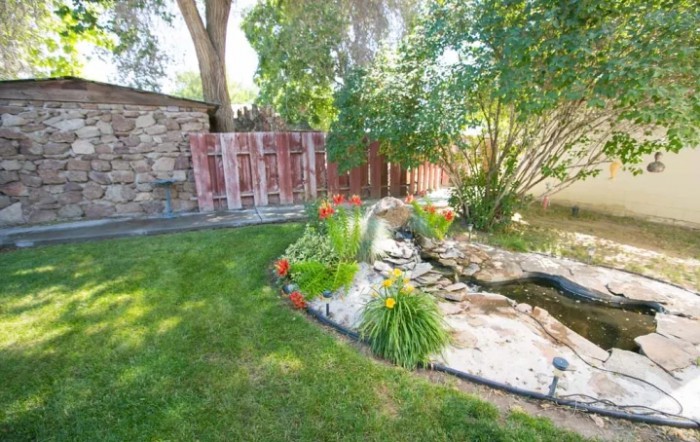 A serene garden featuring a small pond surrounded by greenery and flowers.