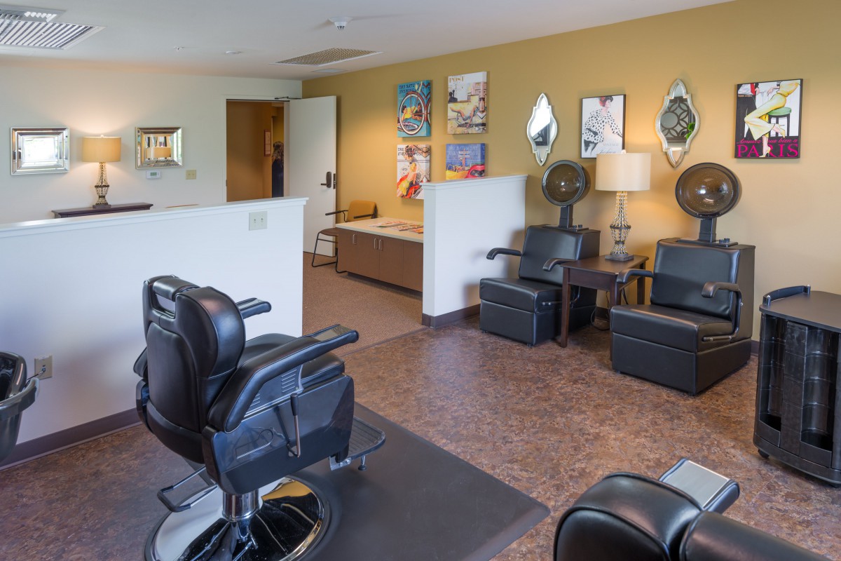 A well-furnished barbershop interior with chairs, mirrors, and a waiting area.