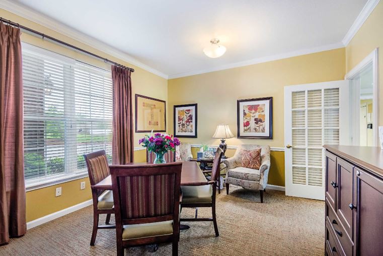 A cozy dining room with a table set for four, adorned with fresh flowers and decorated with artwork.