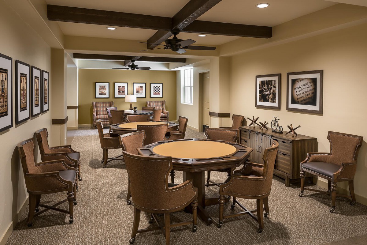 A cozy game room with card tables, chairs, and framed artwork on the walls.
