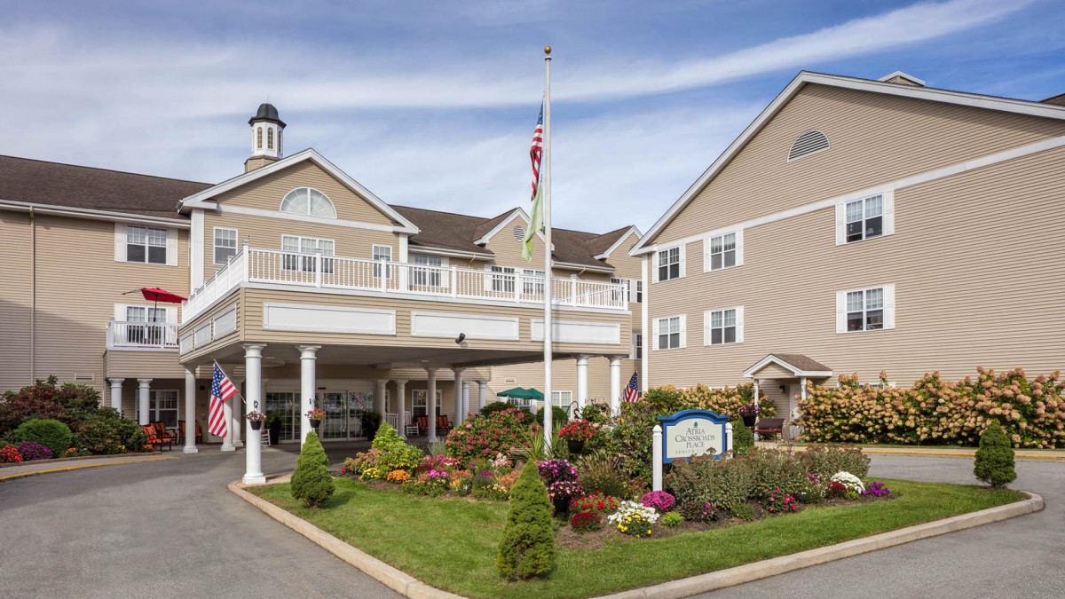 A residential building with a landscaped entrance and flagpole in the front yard.