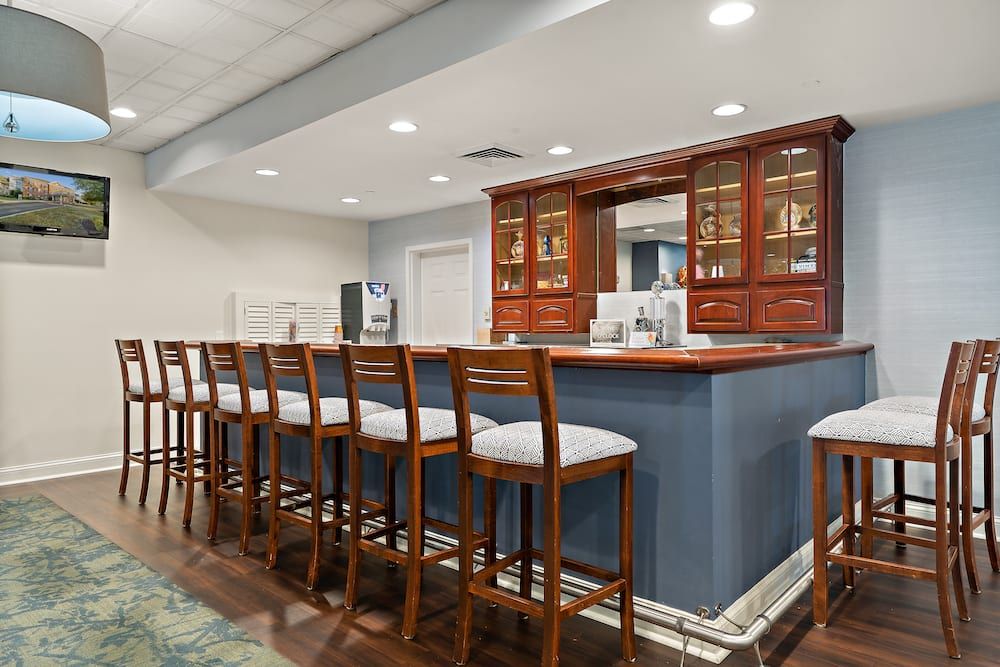 A modern bar interior with wooden chairs lined up along the counter.