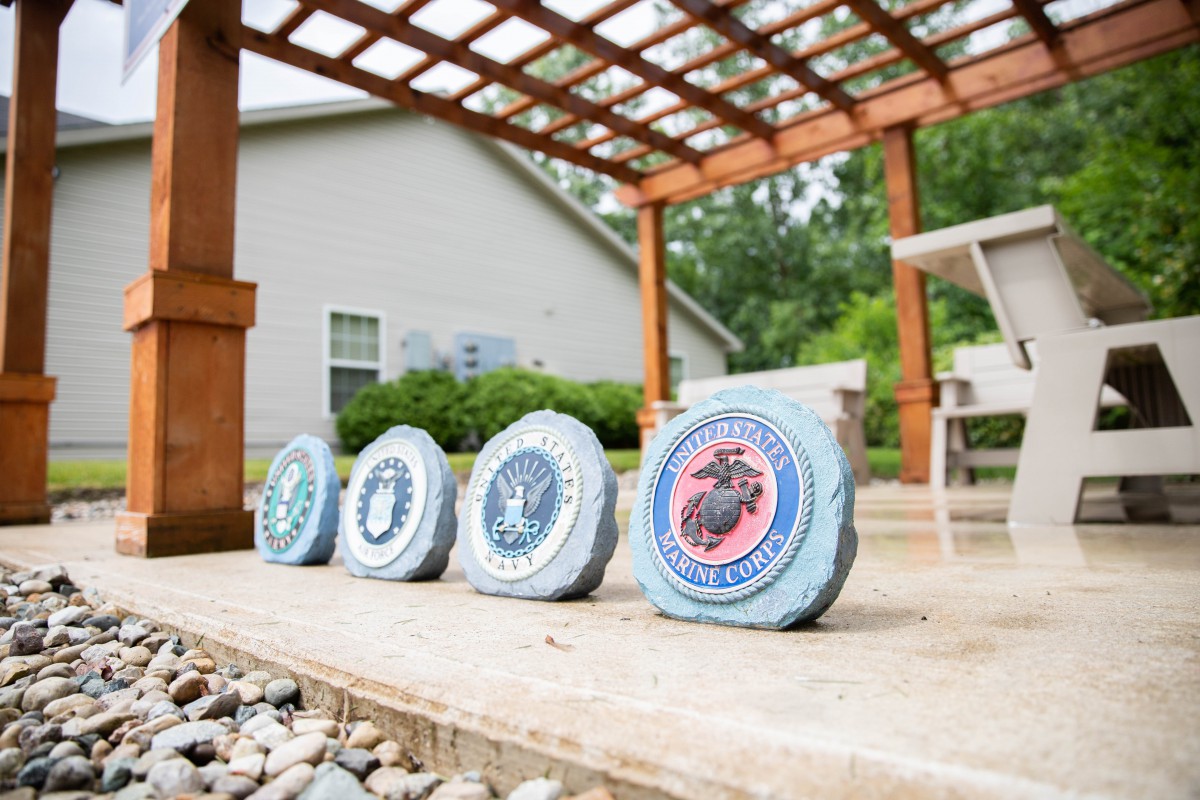 Decorative stones featuring military emblems placed on a patio under a wooden pergola.
