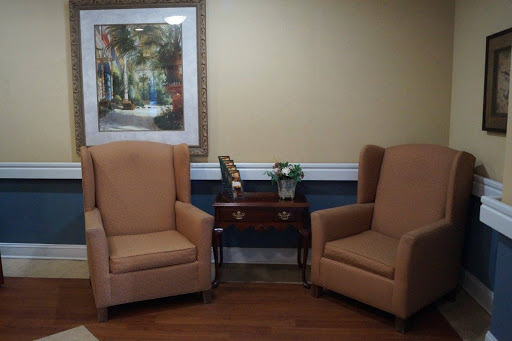 A cozy seating area featuring two upholstered chairs and a small side table with artwork on the wall.