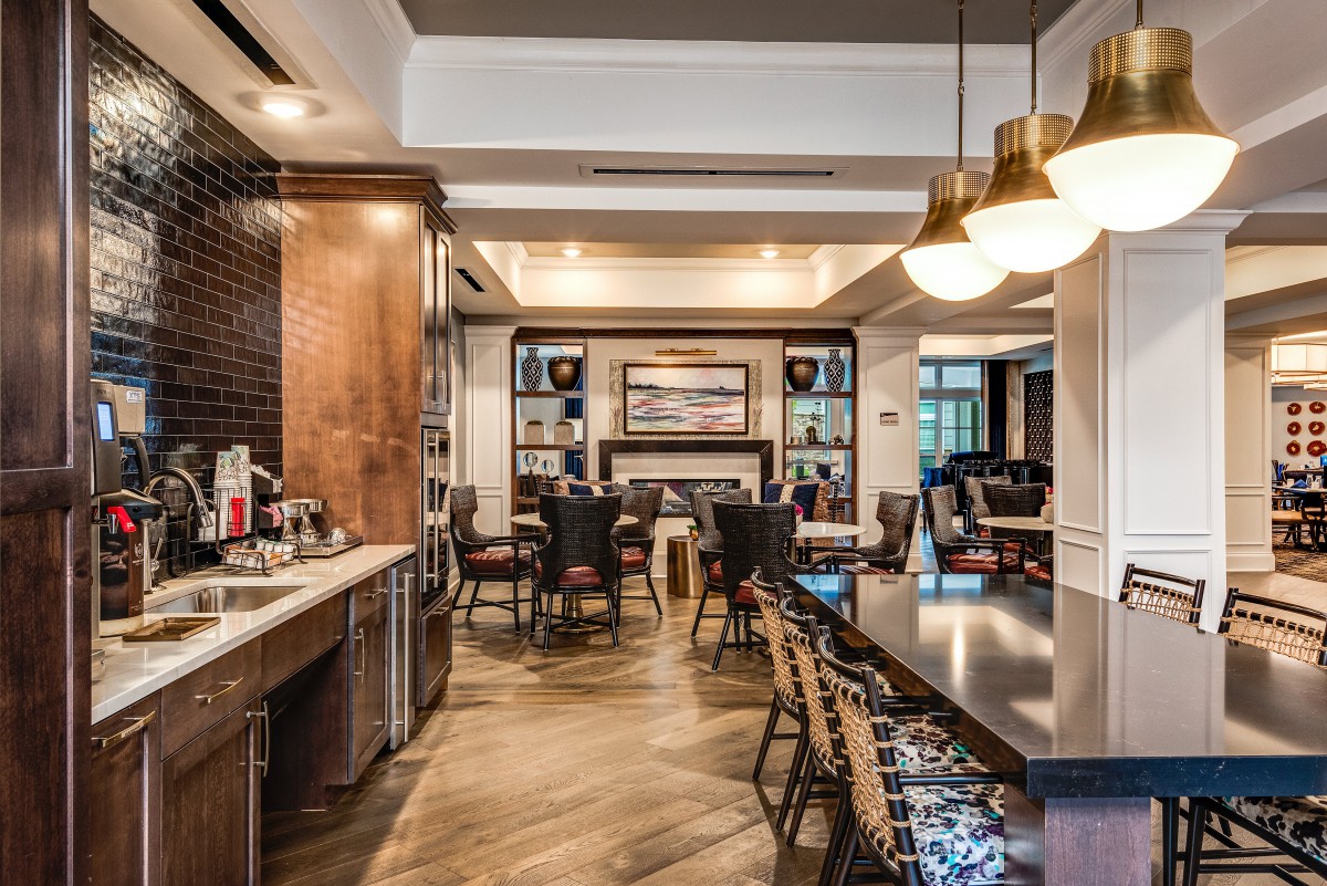 A modern and cozy restaurant interior featuring a mix of dining and bar seating with elegant lighting fixtures.