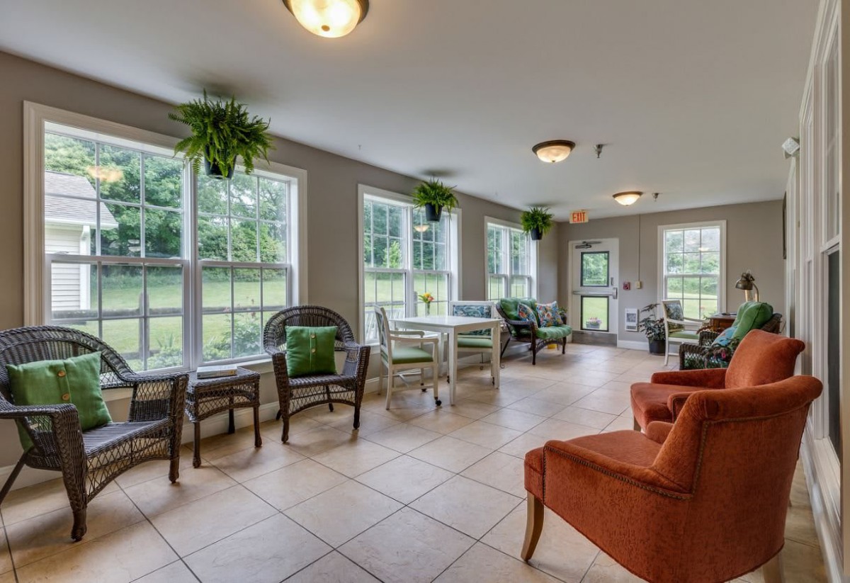 A bright and cozy living area with large windows, comfortable seating, and decorative plants.