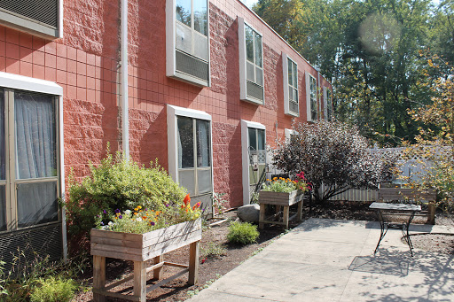 A vibrant apartment building with potted plants and greenery in the foreground.