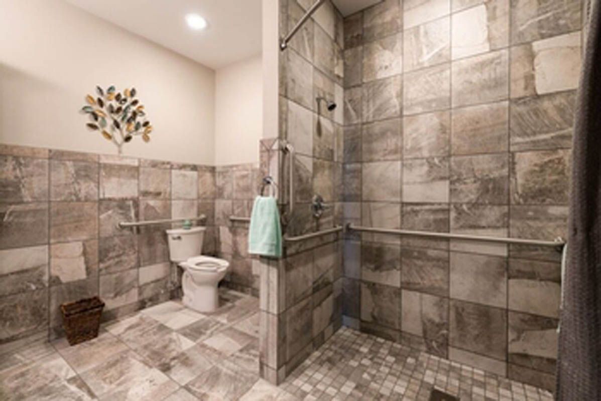 A modern bathroom with tiled walls and flooring, featuring a walk-in shower and toilet.