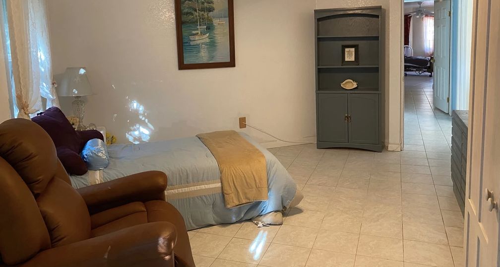 A cozy bedroom with a neatly made bed, a cabinet, and a painting on the wall.