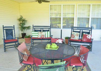 A cozy patio setup with a round metal table, colorful cushions, and decorative plants.