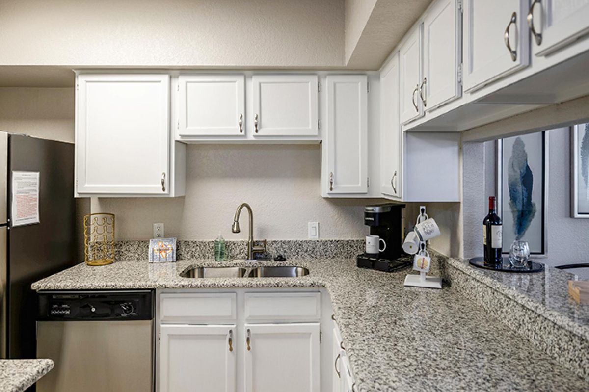 A modern kitchen with white cabinets and granite countertops.