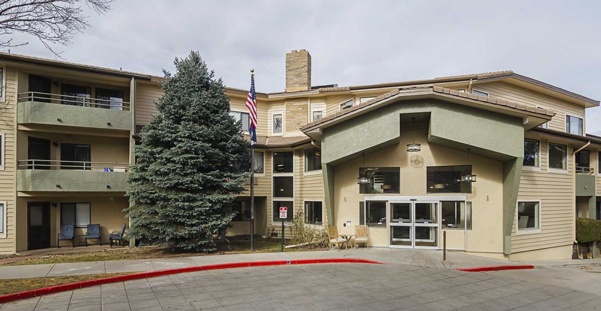 A building entrance with a flag and trees in the foreground.