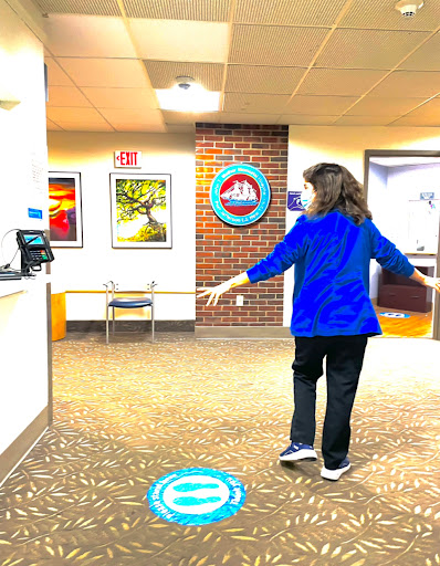 A woman in a blue shirt walks through a hospital's reception area, surrounded by artwork.