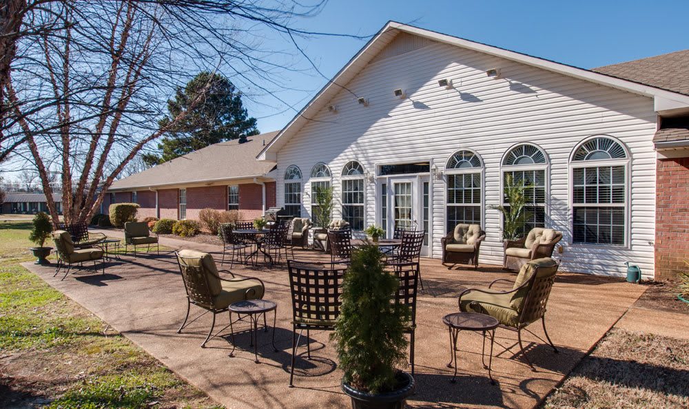 A sunny patio area with chairs and tables outside a building.
