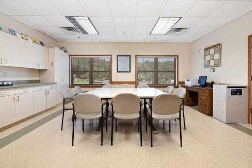 A spacious meeting room equipped with a long table, chairs, and a computer workstation.
