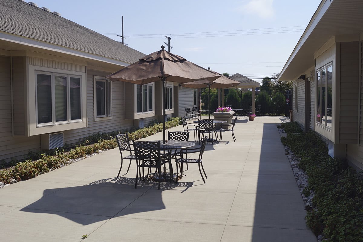 A sunny outdoor patio area with tables, chairs, and umbrellas.