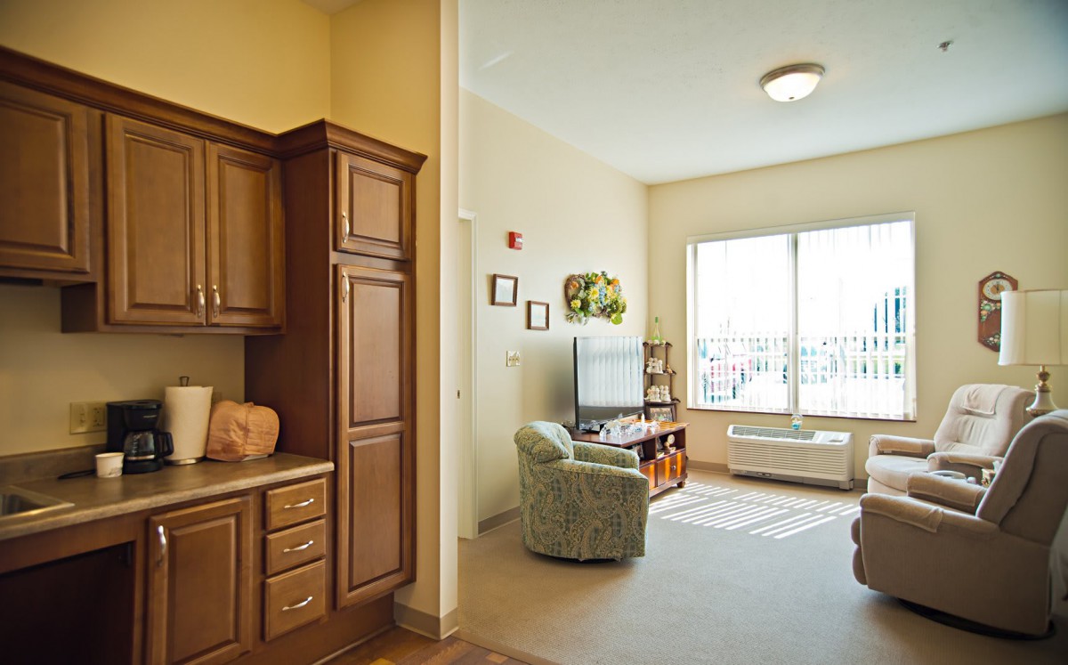 A cozy living room with a view, featuring a television and comfortable seating adjacent to a kitchen area.