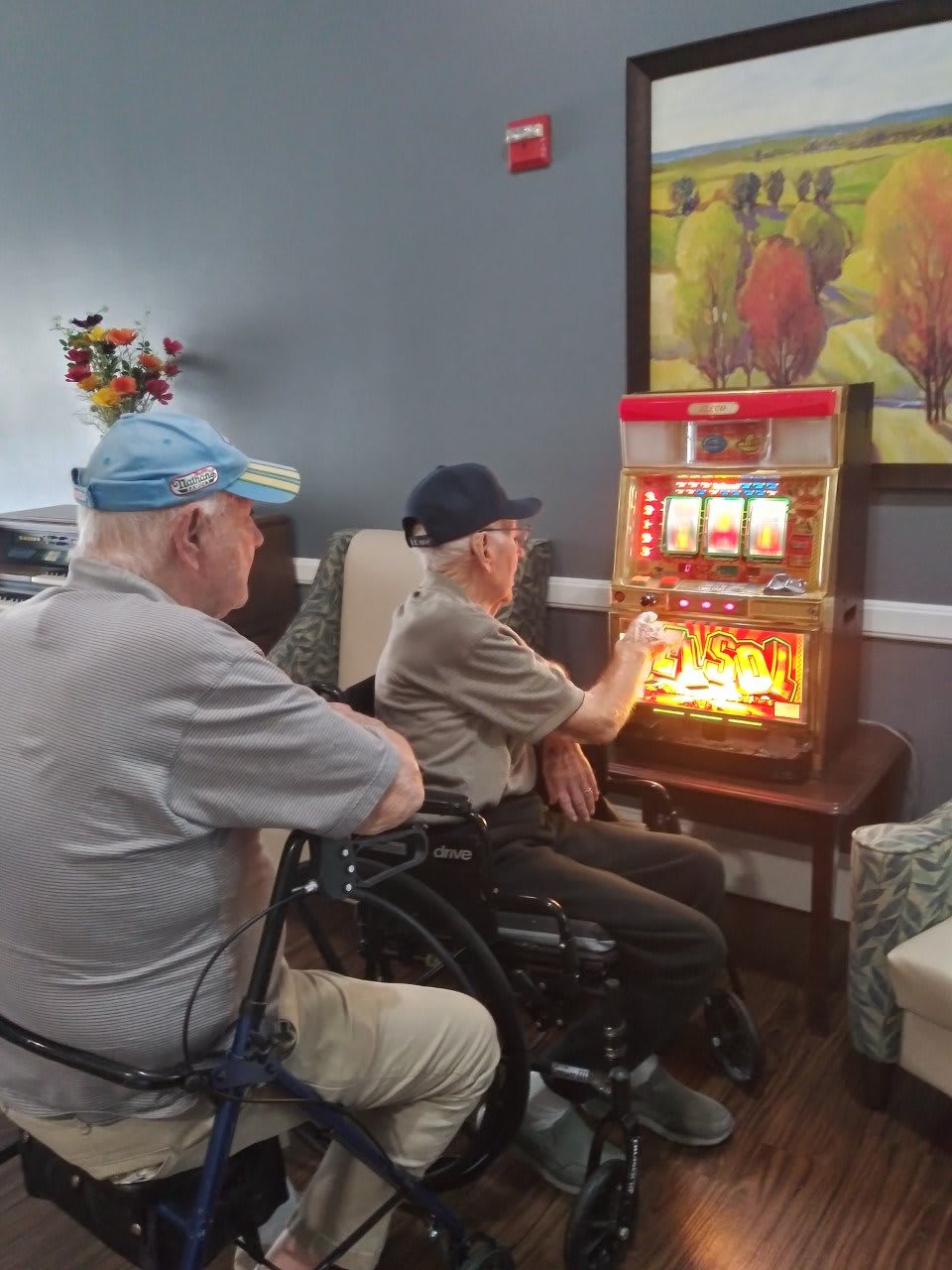 Two elderly men enjoying a slot machine game indoors.