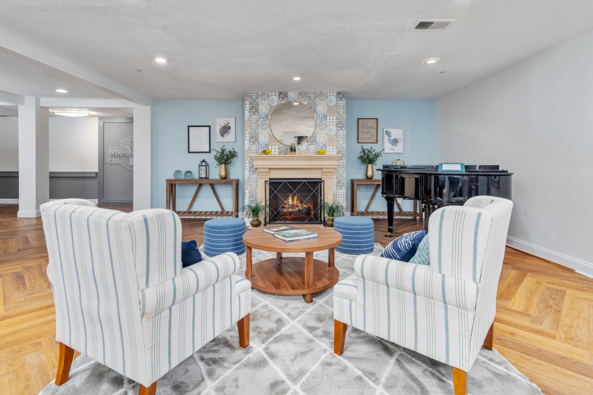 A cozy living room featuring a fireplace, armchairs, and a coffee table in a well-decorated setting.