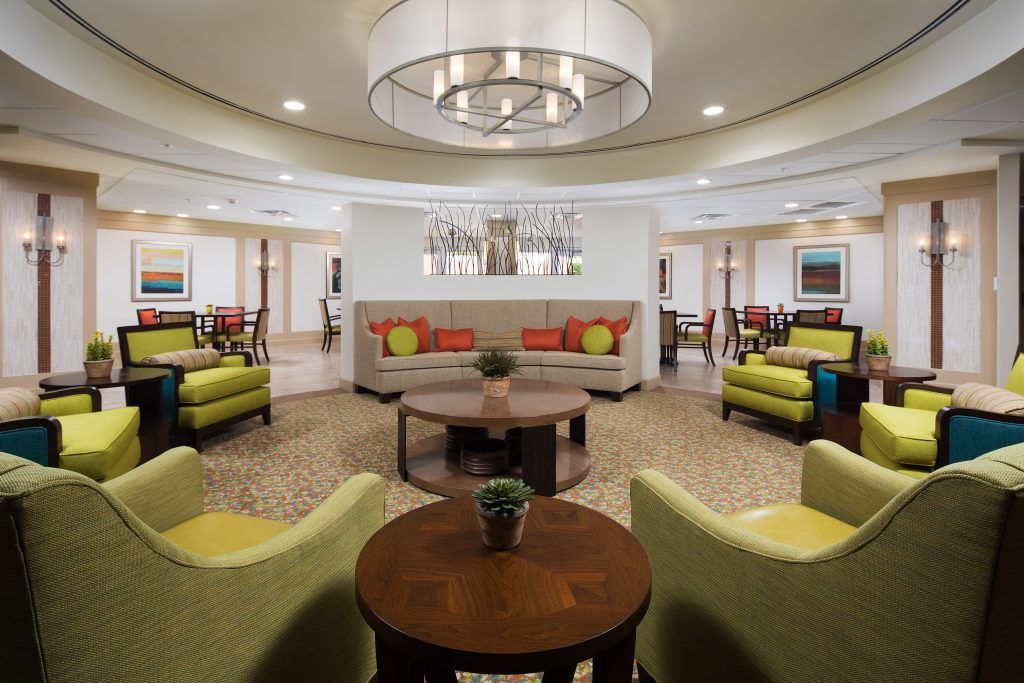 A modern lobby area with comfortable seating and a central chandelier.