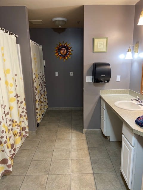 A shared bathroom space with sinks, mirrors, and shower stalls.