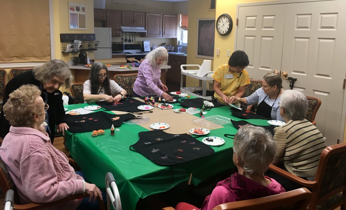 A group of seniors engaged in a crafting activity around a table indoors.