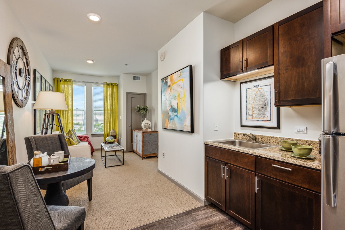 A modern living room with bright decor, featuring artwork on the walls and wood cabinets.
