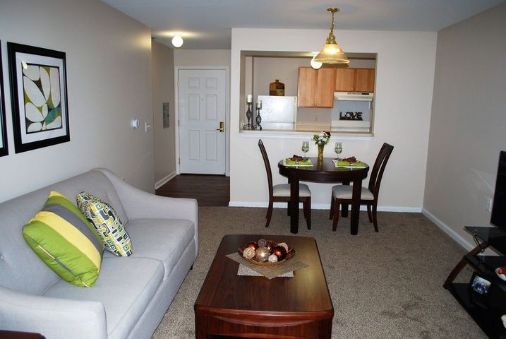 A cozy apartment interior featuring a living room, dining area, and kitchen.