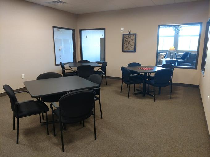 An office meeting room with several tables and chairs arranged for group seating.