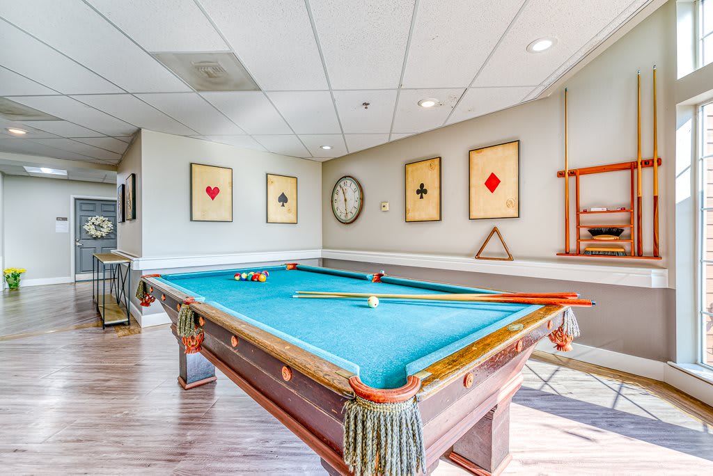A well-lit game room with a pool table, decorated with playing card-themed artwork on the walls.