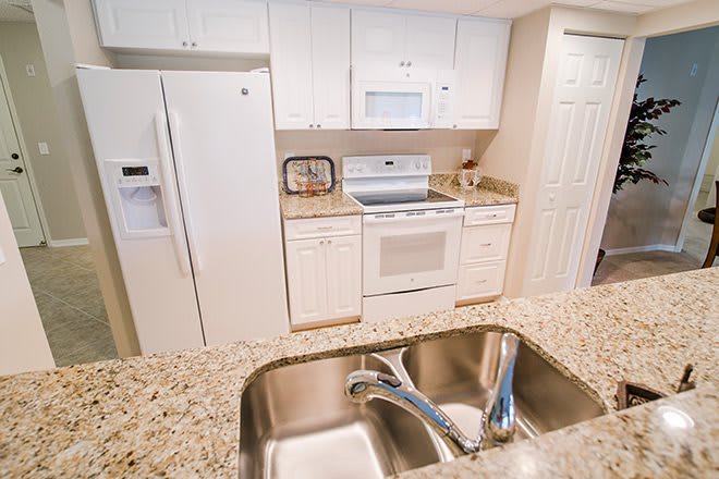 A modern kitchen with white cabinetry, granite countertops, and stainless steel appliances.