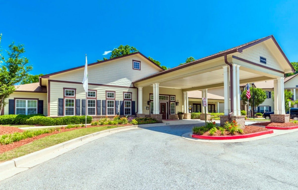 An exterior view of a building with a covered entrance and landscaped surroundings.