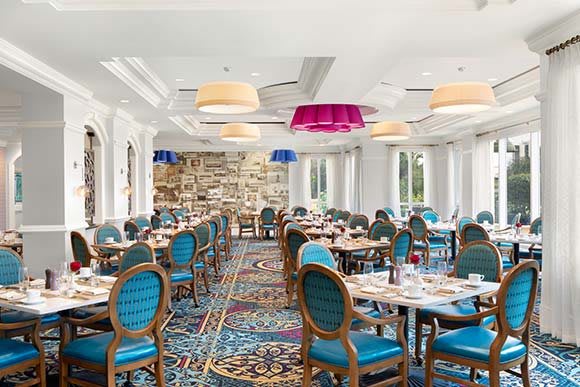A stylish and elegant restaurant dining room with colorful lighting and well-arranged tables and chairs.