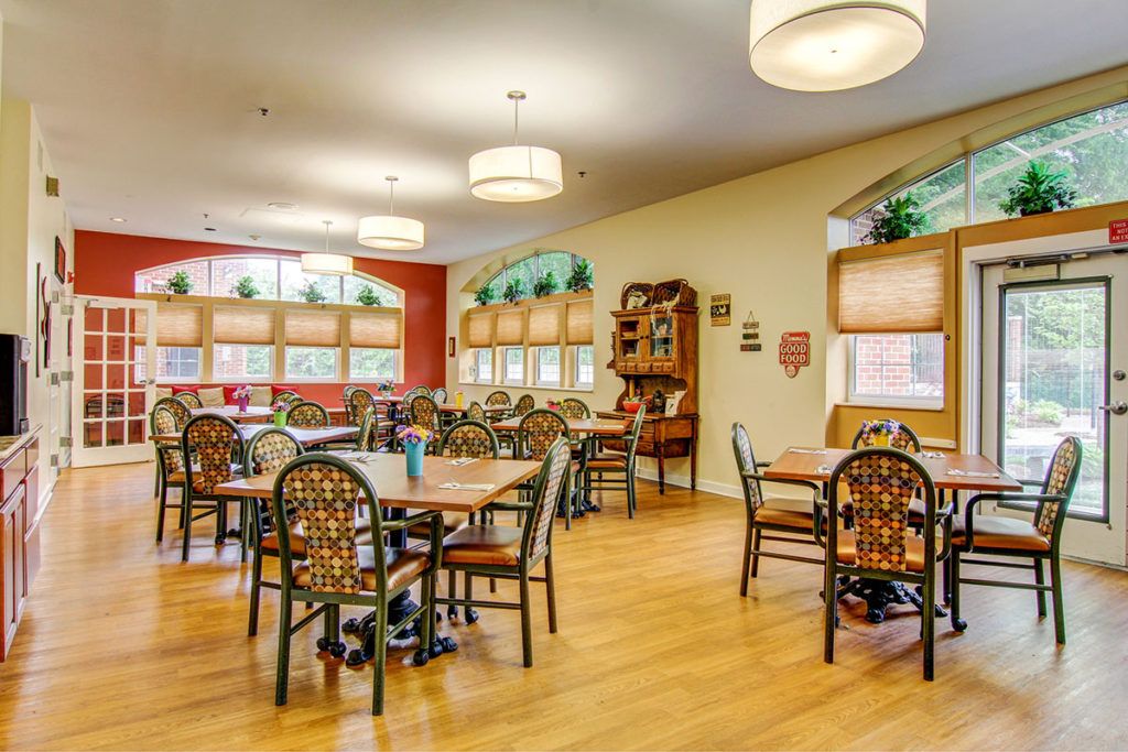 A cozy dining area featuring several tables and chairs, illuminated by decorative overhead lights.