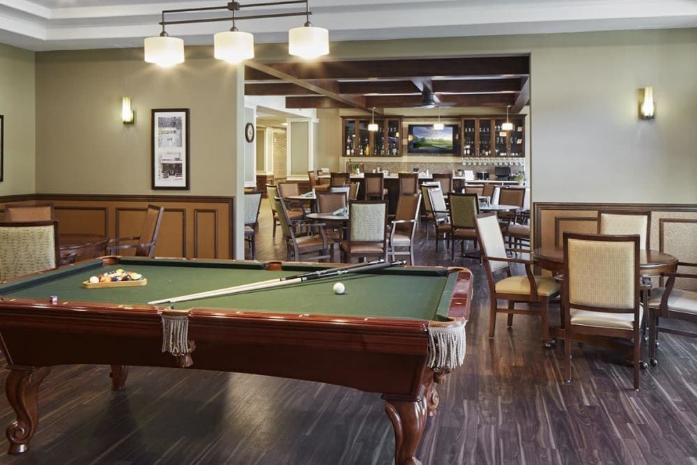 A cozy bar and lounge area featuring a pool table, ample seating, and warm lighting.