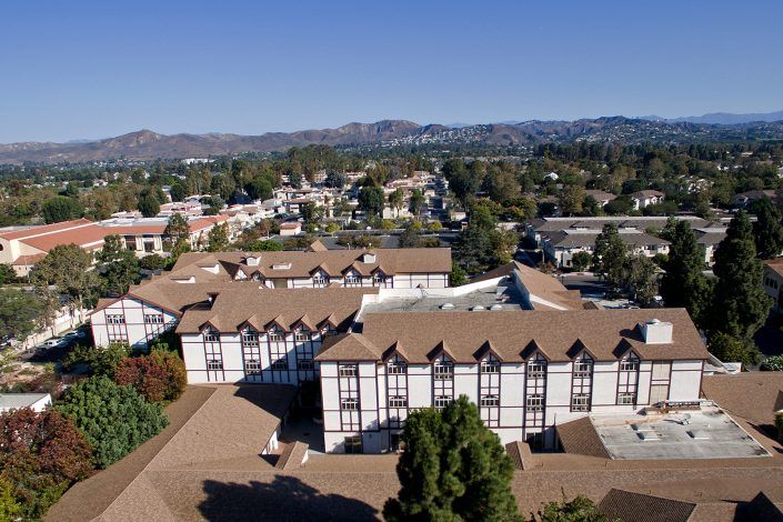 Aerial view of a suburban area with distinctive buildings and mountains in the background.